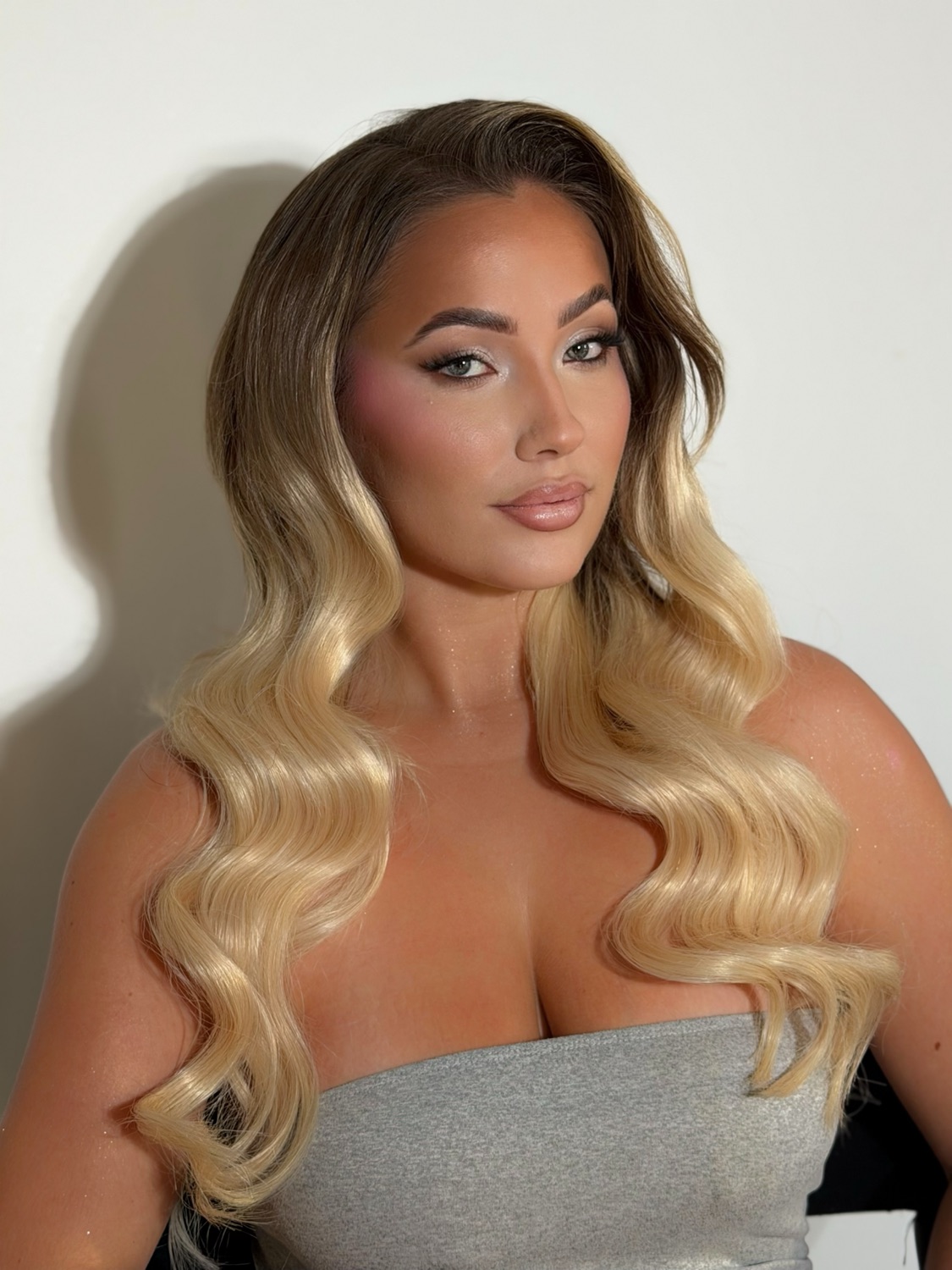 Maquillage glam lumineux réalisé par Bloom, cheveux blonds ondulés